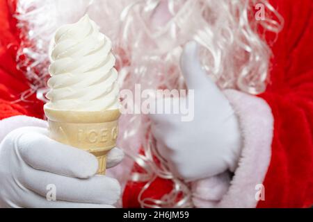 babbo natale una mano tiene un cono gelato e l'altra mano con i pollici in su Foto Stock