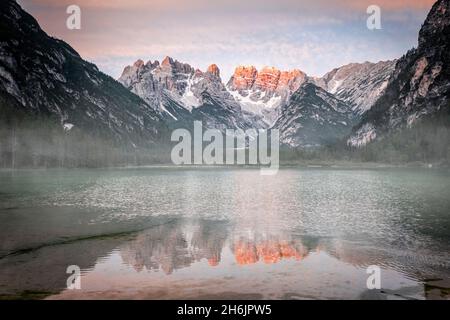 Il gruppo Popena e il Monte Cristallo si specchiano nel lago Landro (Durrensee) nella nebbia all'alba, Dolomiti, Alto Adige, Italia, Europa Foto Stock