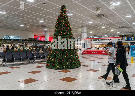 GATWICK LONDRA, REGNO UNITO. 16 novembre 2021. I passeggeri camminano davanti a un albero di Natale decorato è installato nel Terminal Nord in un tranquillo aeroporto di Gatwick. Il governo del Regno Unito ha in programma di introdurre il requisito covid -19 booster jab per viaggiare senza restrizioni . Credit: amer Ghazzal/Alamy Live News Foto Stock