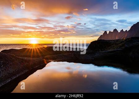 Sole di mezzanotte sul fiordo e sulle cime di montagna conosciute come denti del diavolo, punto di osservazione di Tung-Geneset, Senja, contea di Troms, Norvegia, Scandinavia, Europa Foto Stock