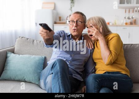 Shocked Senior Couple che guarda Horror Movie Switching Channels a casa Foto Stock