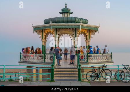 Vista della gente sul palco ornato sul fronte del mare al crepuscolo, Brighton, Sussex orientale, Inghilterra, Regno Unito, Europa Foto Stock