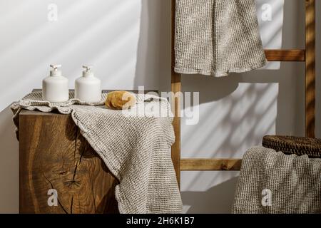 Biancheria da bagno biologica per cialde, dispenser di sapone e lozione, spugna di mare su moncone di quercia massello in bagno moderno interno. Cura giornaliera del corpo, spa e benessere Foto Stock