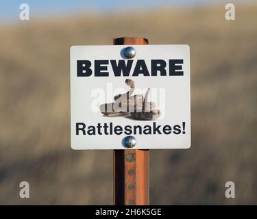 Attenzione al cartello Rattlesnakes sul posto al Badlands National Park nel South Dakota Foto Stock