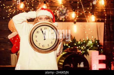 Tempo per la festa invernale. Donna Santa cappello tenere orologio vintage. È il momento di festeggiare. Conto alla rovescia per il nuovo anno. Inaspettatamente presto. Concetto di mezzanotte. Fai il desiderio Foto Stock