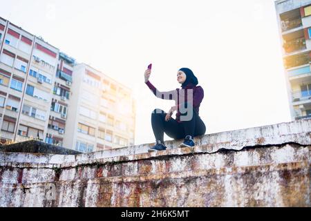 Giovane donna mediorientale che prende un selfie durante il suo allenamento mattutino Foto Stock