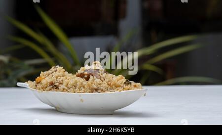 Beef Biriani - riso cotto con spezie, tenuto su un tavolo con sfondo verde Foto Stock