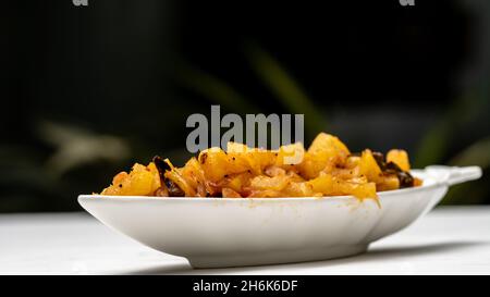 Chutney di ananas in piatto/recipiente bianco su un tavolo con sfondo verde esterno. Foto Stock