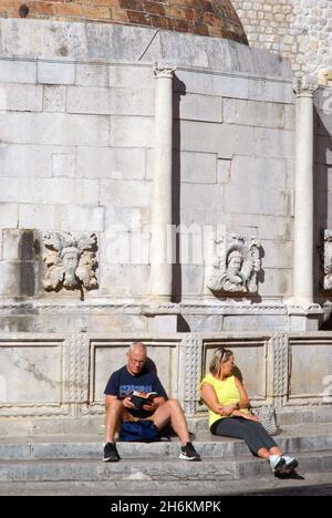 La gente sedeva accanto alla grande Fontana di Onofrio, Dubrovnik, Croazia. Foto Stock
