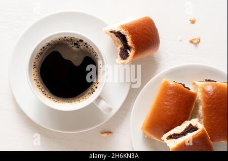 Tazza di caffè nero con ciambelle di confettura di prugne ceca su bianco. Vista dall'alto. Foto Stock