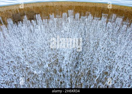 Un muro di diga con acqua traboccante. Foto Stock