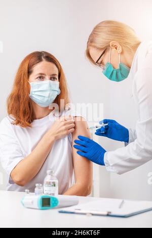 Donna vaccinata in clinica Foto Stock
