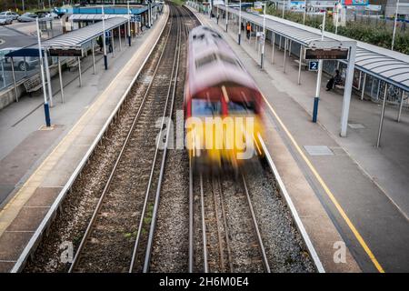 Treno in accelerazione che attraversa la stazione (movimento sfocato) Foto Stock