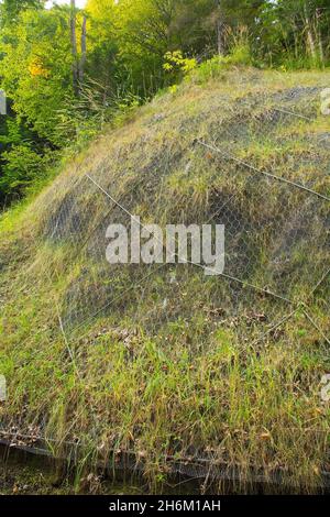 Rete di protezione contro le pendenze a maglia su Monte Ruke, ne Italia. Un sistema di stabilizzazione utilizzato per fissare rocce sciolte e rocce instabili Foto Stock