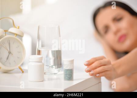 Donna malata che prende le pillole a casa Foto Stock