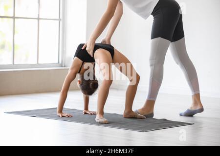 Allenatore aiutare la bambina a fare ginnastica in palestra Foto Stock