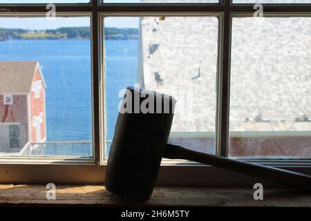 Primo piano di un antico martello in legno sul davanzale, con la luce del sole che entra attraverso la finestra. Visualizza attraverso la finestra. Foto Stock