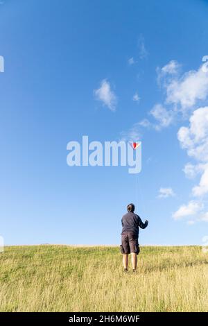 Uomo che vola un aquilone su una collina Foto Stock