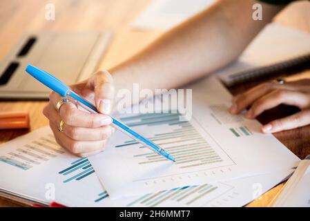 Primo piano del grafico di puntamento della mano di una donna d'affari in ufficio Foto Stock