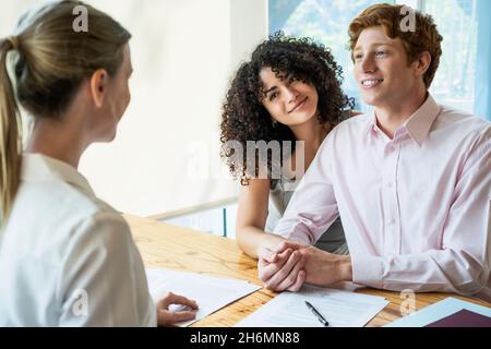 Giovane coppia firma contratto in ufficio Foto Stock