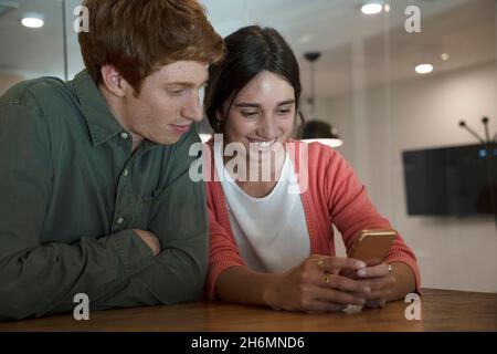 Uomo e donna che utilizzano lo smartphone in ufficio Foto Stock