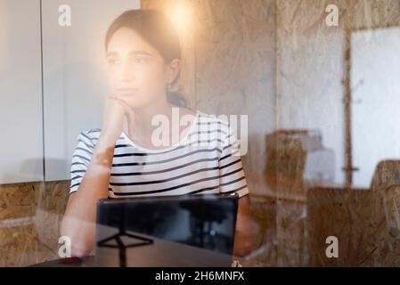 Riflessivo imprenditrice seduta in ufficio Foto Stock