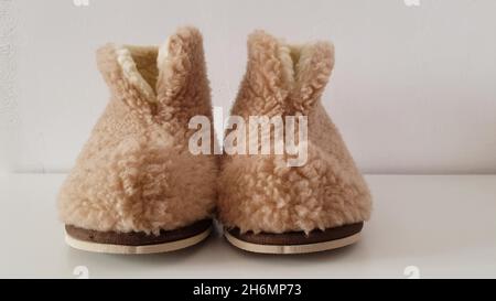 Calde pantofole invernali in pelle di pecora sul pavimento bianco. Foto Stock
