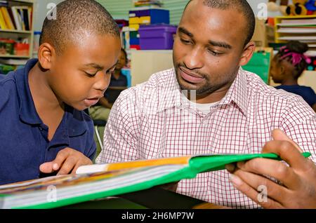 Un insegnante di sesso maschile aiuta uno studente di scuola elementare con una lezione di lettura, il 4 ottobre 2011, a Columbus, Mississippi. Foto Stock