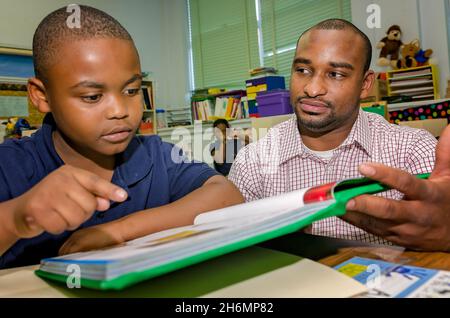 Un insegnante di sesso maschile aiuta uno studente di scuola elementare con una lezione di lettura, il 4 ottobre 2011, a Columbus, Mississippi. Foto Stock