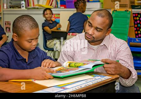 Un insegnante di sesso maschile aiuta uno studente di scuola elementare con una lezione di lettura, il 4 ottobre 2011, a Columbus, Mississippi. Foto Stock