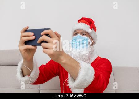 Vestito come Babbo Natale che parla tramite videoconferenza Foto Stock