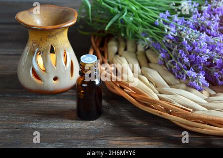 Fiori freschi di lavanda con bottiglia di olio essenziale e una lampada per oli aromatici su un tavolo di legno. Aromaterapia e concetto spa. Foto Stock