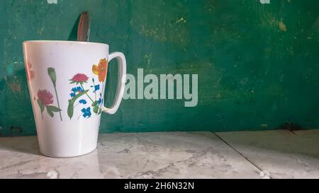 shot di tazza di caffè contro la parete verde Foto Stock