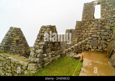 Vista del bagnato edificio in parte residenziale a Machu Picchu, Perù durante la pioggia. Machu Picchu è un'icona della civiltà Inca. Foto Stock