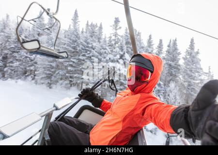 Vacanza sci - sciatore in skilift prendendo selfie foto o video utilizzando il telefono cellulare. Sci invernale concetto vacanza. Sciare sulle piste da neve in montagna Foto Stock