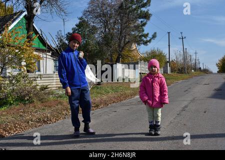 Verkhnotoretske, Donetsk, Ucraina. 16 ottobre 2021. I bambini veduto in piedi sulla strada con legna alla periferia del villaggio.Verkhnotoretske è una città Ucraina situata vicino alla linea anteriore nel distretto di Yasynuvata nell'oblast di Donetsk, Ucraina orientale. Durante la guerra di Donbas, iniziata a metà aprile 2014, la linea di divisione tra le parti in guerra si trovava nelle vicinanze dell'insediamento. Il villaggio era una zona grigia fino alla fine del 2017. Oggi Verkhnotoretske è territorio ucraino. (Credit Image: © Andriy Andriyenko/SOPA Images via ZUMA Press Wire) Foto Stock