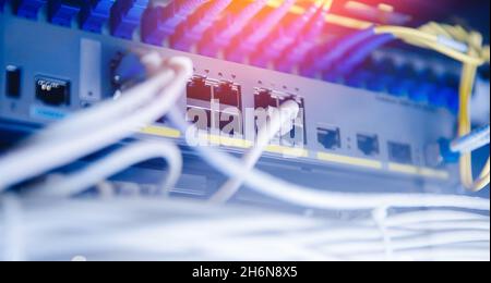 Pannello Business Network con switch e cavo rj45 su sfondo blu del data center. Interfaccia connettore Concept. Foto Stock