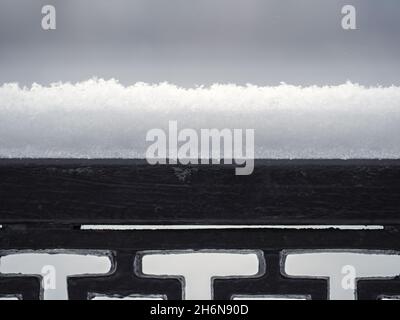 Recinzione in ghisa metallica sotto la neve. Frammento di una recinzione forgiata coperta di neve. Reticolo decorativo in ferro ricoperto di neve Foto Stock