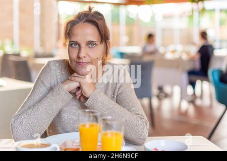 Vista frontale di una donna adulta che fa colazione in hotel. Foto Stock