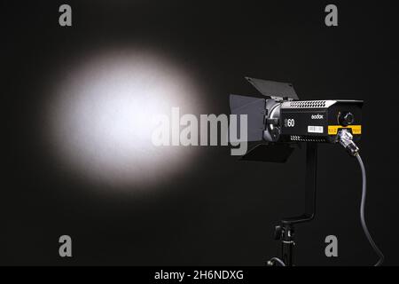 Luce costante monoblocco Godox acceso con refkector su sfondo nero. Lo sfondo è illuminato da un punto di luce e da un fascio di luce Foto Stock