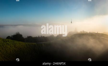 Vista dalla cima del Monte Eden con nebbia che si aggetta sopra il cratere vulcanico e la Sky Tower, la città di Auckland. Foto Stock