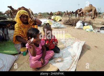 Non esclusiva: PUSHKAR, INDIA - 13 NOVEMBRE 2021: Una donna con i loro bambini durante l'annuale Pushkar Camel Festival, una fiera di bestiame multi-giorno e. Foto Stock