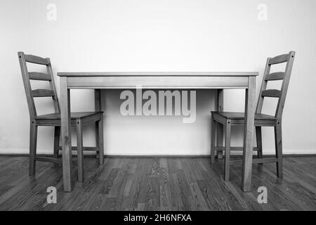 Fotografia in bianco e nero di interni semplici con due sedie di legno e un tavolo su pavimento di legno Foto Stock