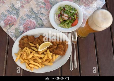 Schnitzel con patatine fritte, piatto di insalate e birra di grano servita su un piatto in un giardino di birra, Baviera, Germania Foto Stock