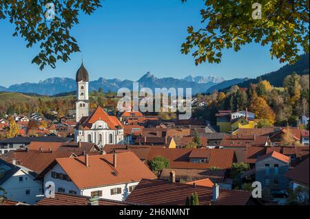 Vista di Nesselwang con Sant'Andrea, chiesa parrocchiale cattolica, a destra il massiccio dello Zugspitze, a sinistra il Saeuling, Baviera, Germania Foto Stock