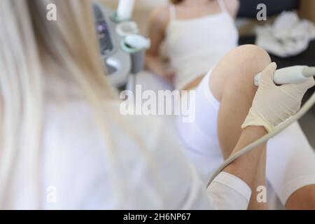 Medico di sesso femminile che conduce l'esame ecografico del ginocchio dei pazienti in clinica Foto Stock