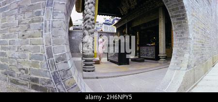 Donna con bastoni di incenso, porta circolare al Tempio Pak Tai sull'Isola di Cheung Chau, Hong Kong, Donna Cina con bastoni di incenso, porta rotonda a. Foto Stock