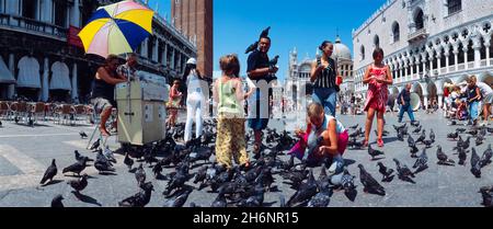 Bambini che nutrono piccioni, Palazzo Ducale, Piazza San Marco, Venezia, Italia Foto Stock