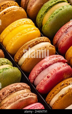 Una fila di macaron luminosi di colore diverso. Primo piano del concetto di pasticceria Foto Stock