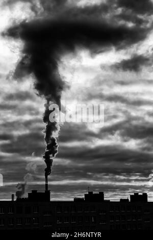 Emissione di vapore nero di concetto bianco e nero sul tubo di una centrale termica con cielo drammatico (St Petersburg, Russia) Foto Stock